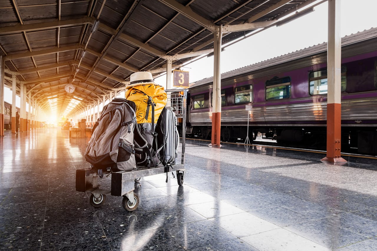 A traveler's baggage cart on an urban railway station platform at sunrise.